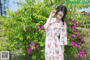 A woman in a white dress standing in front of a house.