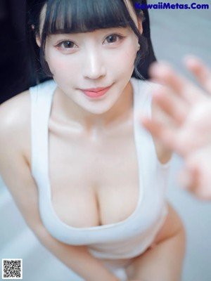 A woman in a white tank top sitting in a bathtub.