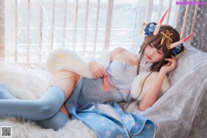 A woman wearing a unicorn horn with flowers in her hair.