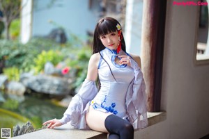 A woman in a blue and white dress is posing for a picture.