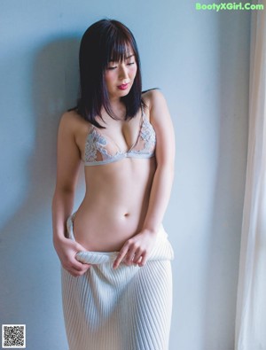 A woman in a black lingerie sitting on a bed.