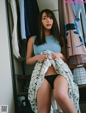 A woman in a blue top and black lingerie posing for the camera.