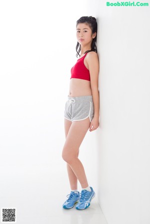 A woman in a red top and gray shorts posing for a picture.