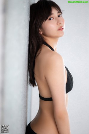 A woman in a black bikini posing for a picture.