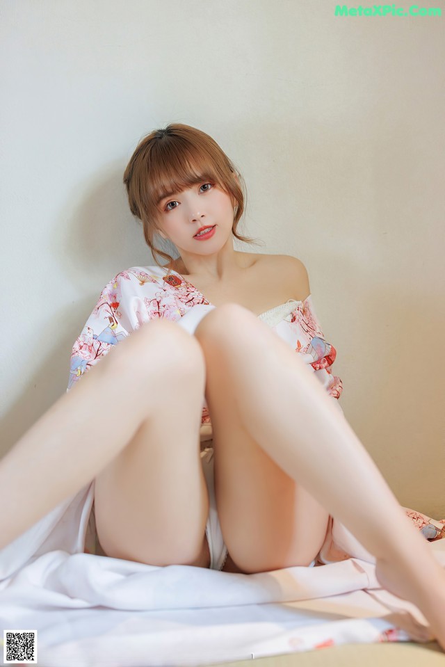 A woman sitting on top of a bed with her legs crossed.