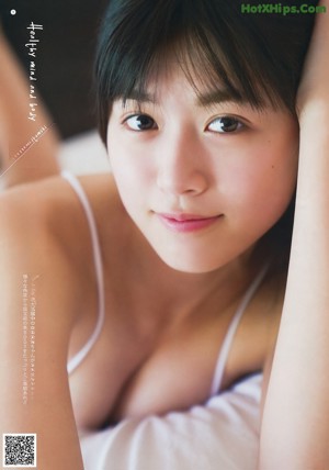 A woman in a white shirt is posing on a bed.