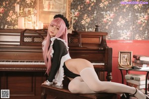 A woman with pink hair is sitting on a couch.
