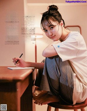A woman in a white shirt and black pants posing for a magazine.