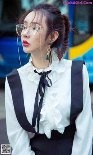 A woman in a white shirt and black skirt talking on a cell phone.
