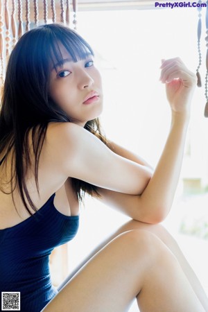A woman in a blue swimsuit sitting on the floor.