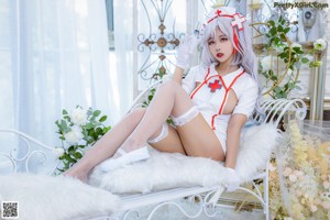 A woman in a white nurse outfit sitting on a white chair.