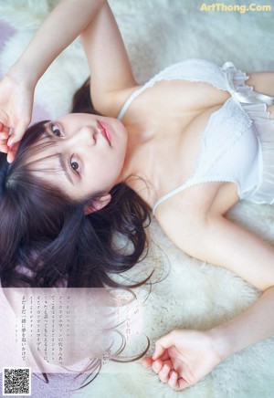 A woman in a white lingerie laying on a white rug.