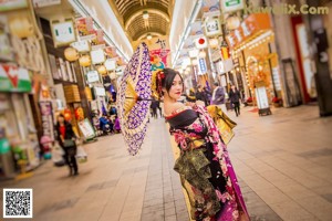 A woman in a kimono holding an umbrella on a city street.