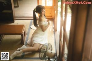 A naked asian woman standing in front of a window.