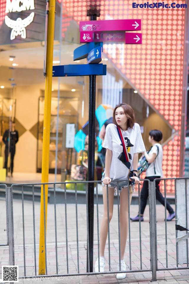 A woman standing in front of a street sign.