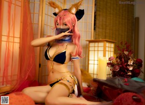 A woman in a cat costume sitting on a bed.