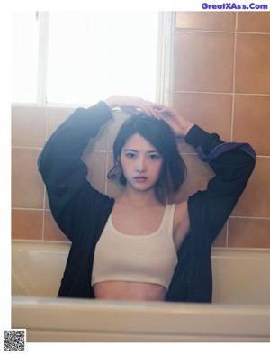 A woman in a blue shirt and black pants posing for a magazine.